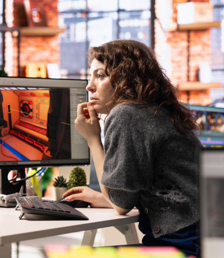 Frau arbeitet nachdenklich an einem Computer mit 3D-Animationssoftware.