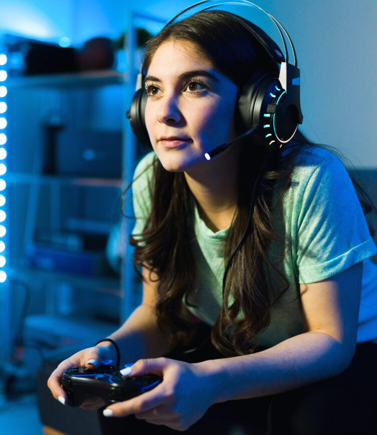 Fokussierte Gamerin mit Headset und Controller spielt ein Videospiel.