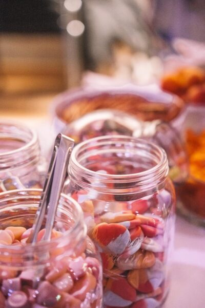 Eine Snack-Auswahl auf einem Tisch mit Schalen voller Chips, Salzstangen, Obst und Süßigkeiten.