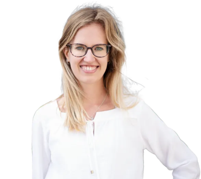 Junge Frau mit langen blonden Haaren und Brille, die lächelnd in die Kamera schaut. Sie trägt eine weiße Bluse und hat ihre rechte Hand in die Hüfte gestützt.