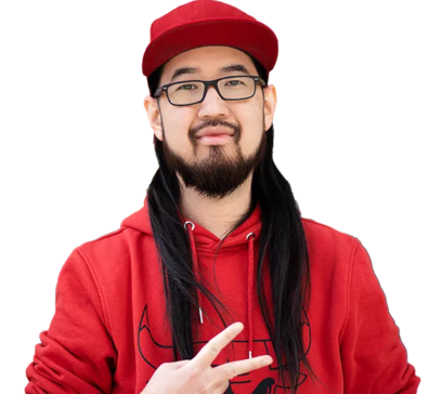 Junger Mann mit langem schwarzen Haar, Bart und Brille, der eine rote Baseballkappe und einen roten Kapuzenpullover trägt. Er zeigt mit der rechten Hand ein Peace-Zeichen. Hintergrund ist weiß.