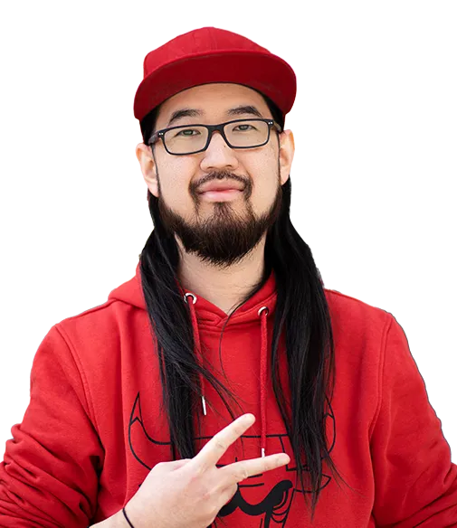 Junger Mann mit langem schwarzen Haar, Bart und Brille, der eine rote Baseballkappe und einen roten Kapuzenpullover trägt. Er zeigt mit der rechten Hand ein Peace-Zeichen. Hintergrund ist weiß.