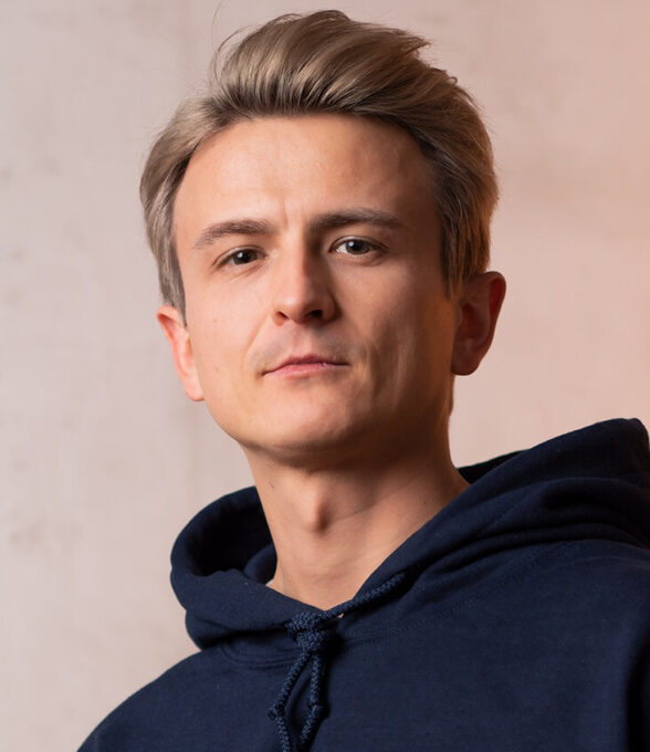Dima Koslowski, Content Creator, trägt einen dunkelblauen Hoodie. Der Kopf ist leicht zur Seite geneigt.