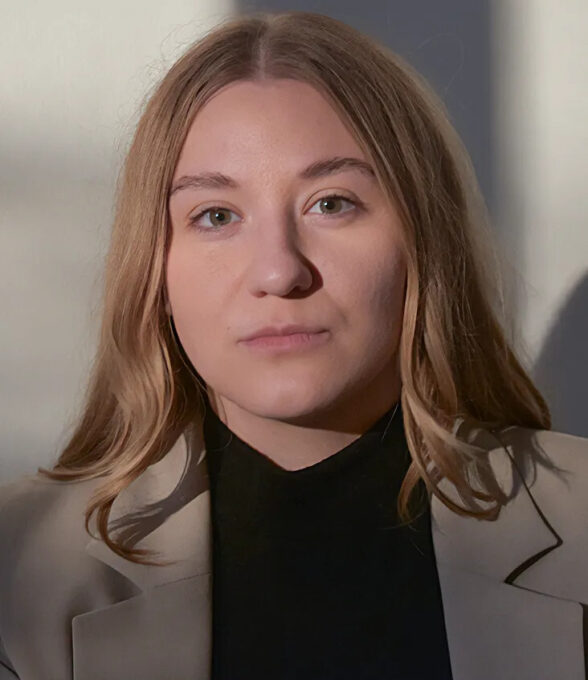 Larena Kloeckner trägt einen schwarzen Pullover und einen beigen Blazer. Ihr Haar ist lang und blond.