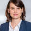 Miriam Goetz hat kurze fast schulterlange braune Haare und trägt einen blauen Anzug.